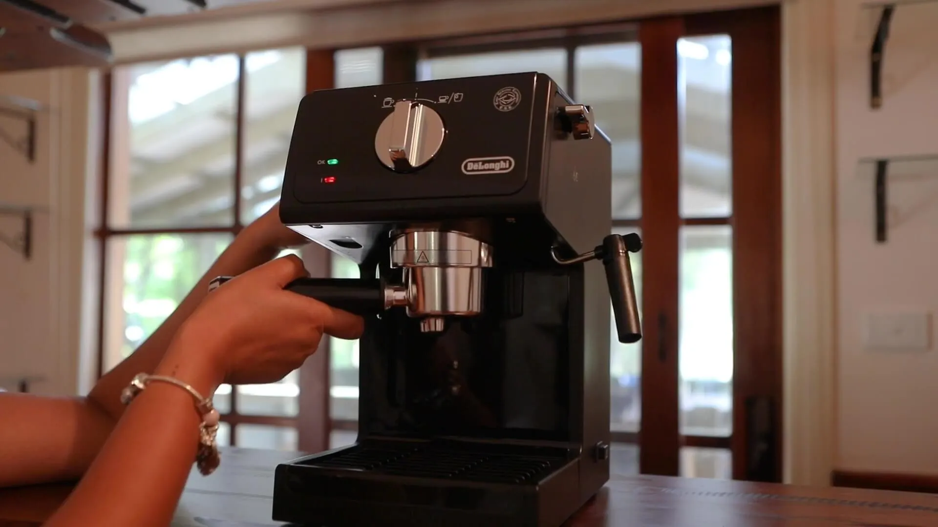 Hands working an espresso machine at the kitchen bench.