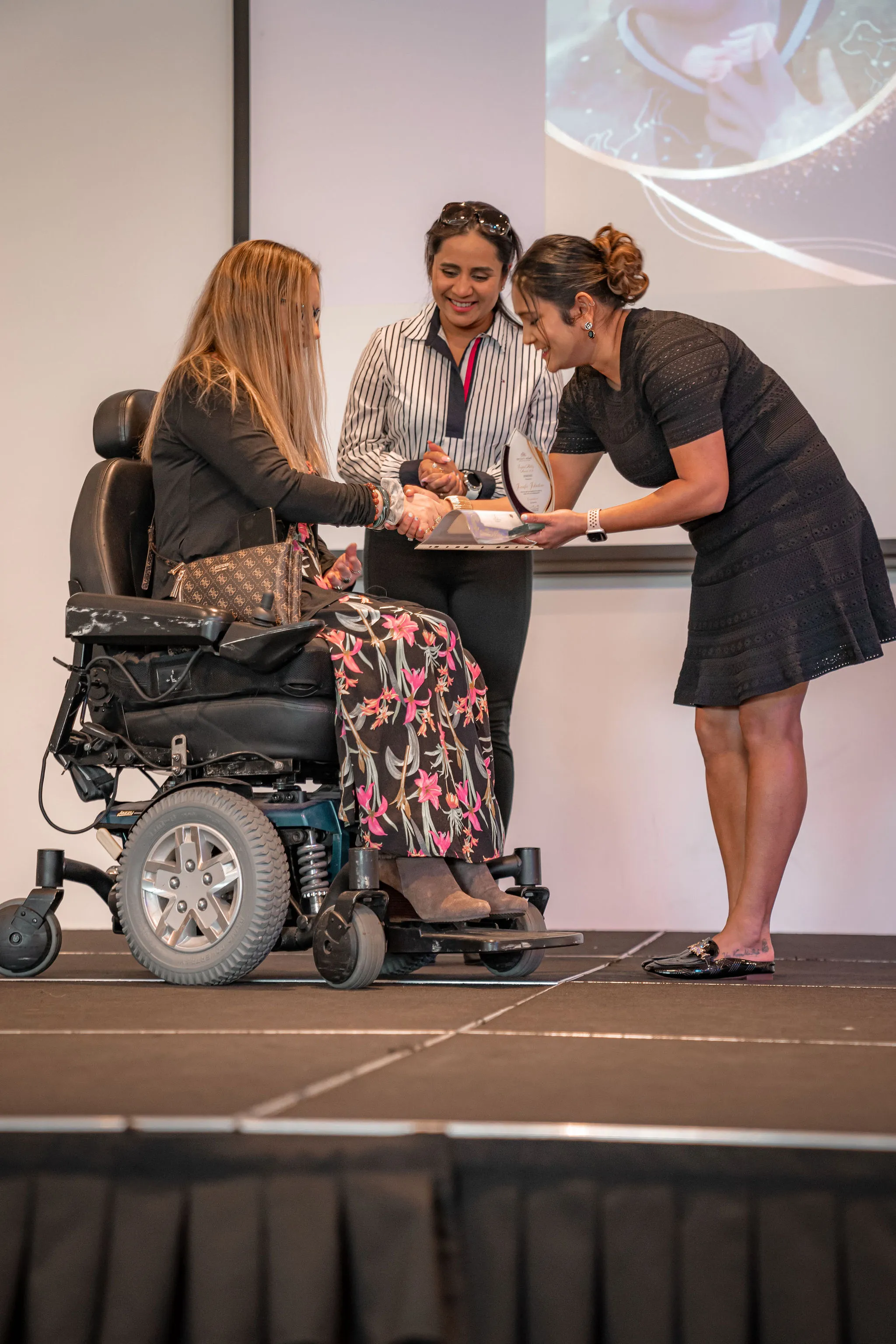A presenter handing an award to a resident in a wheelchair.