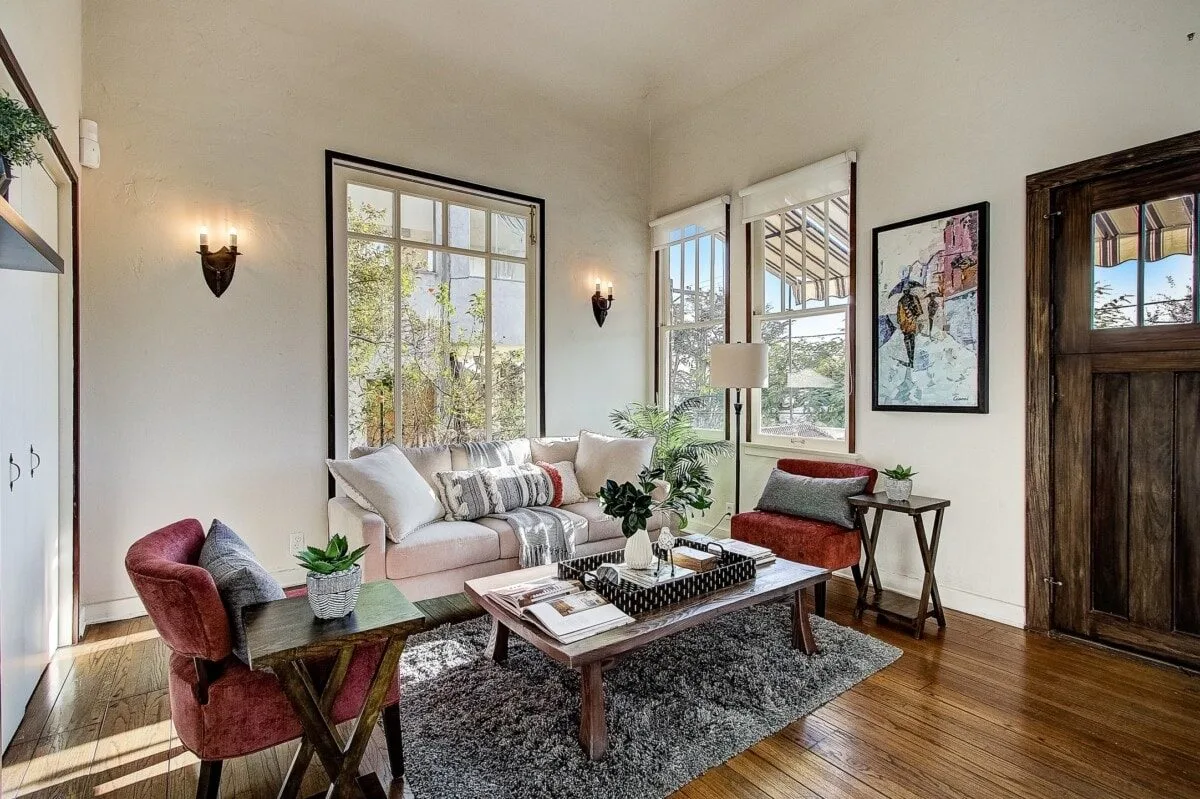 A bright living room with tall windows, plants and warm timber floors.