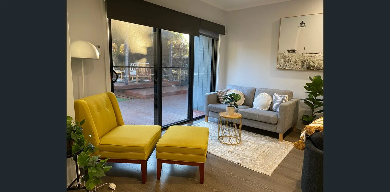 A Second Home living room with yellow armchairs and a view to the deck.