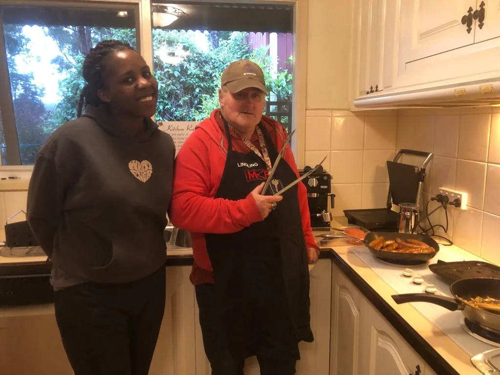 Two team members in the kitchen, sharing a laugh while cooking.